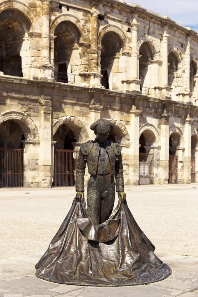 Statue of Nimeño II, with the Arena of Nîmes in the background Statue of Nimeño II, with the Arena of Nîmes in the background
